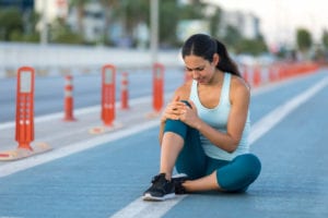 Female runner clutching injured knee