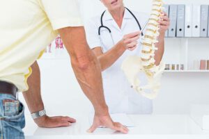 Doctor showing her patient a spine model in medical office