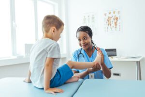 Female orthopedist examining little child foot condition in clinic