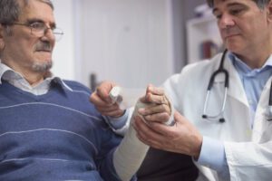 orthopedic injury doctor doing bandages of patient hand injury