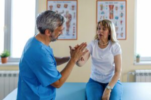 An orthopedic doctor examines the hand pain of a senior female patient at the clinic.