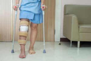 Patient standing on crutch in hospital ward after ACL surgery