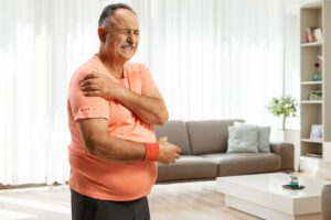 A mature man grimaces in pain, holding his shoulder due to rotator cuff tears.