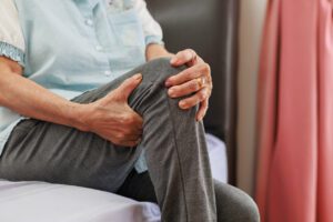 An elderly person is holding their knee in pain and is seeking relief for knee discomfort.
