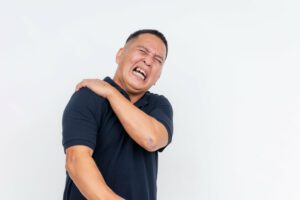 A middle-aged man suffering from severe shoulder pain, caused by rotator cuff injury.