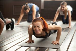 Woman doing difficult plank exercise or pushups has muscle strain pain