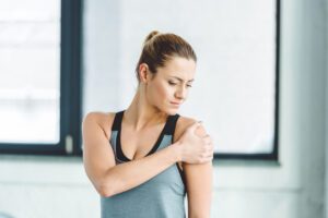 Image of a of young sportswoman experiencing shoulder pain from her hurt rotator cuff.