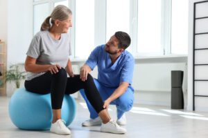 An orthopedic doctor working with senior patient with knee arthritis in rehabilitation center.
