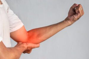 Pain in the elbow joint of a young man, which is caused by Golfer's elbow.